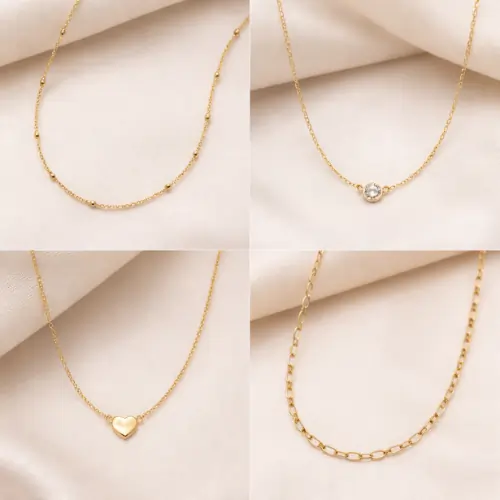 Four lightweight gold necklaces including beaded chain, solitaire pendant, heart pendant, and link chain on soft beige fabric background