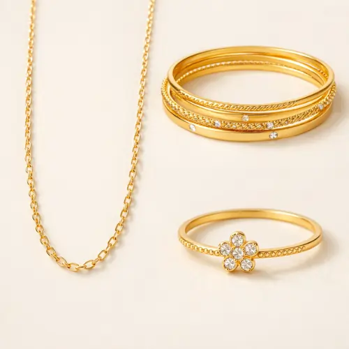 Lightweight gold chain necklace with stacked gold bangles and floral diamond ring on neutral background